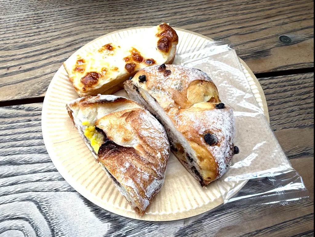 木桌上纸盘里的三块糕点，旁边有透明塑料包装袋。
