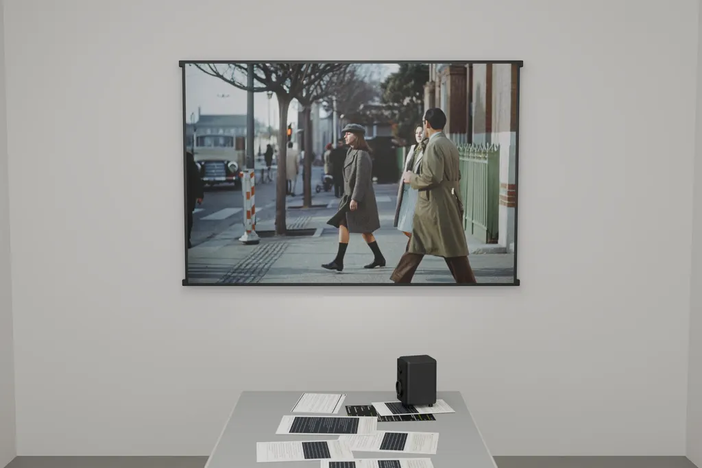 Installation rendering facing the framed AI-generated still, with the evidence table and one small studio monitor in the foreground.