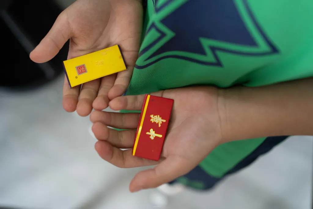 Close-up of a child's open hands holding yellow and red rectangular game pieces.