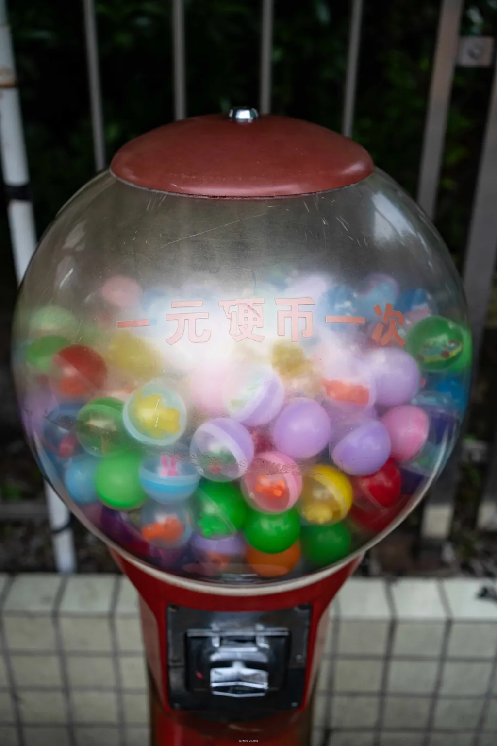 Plastic capsule toy machine filled with colorful balls, with Chinese text on the globe.