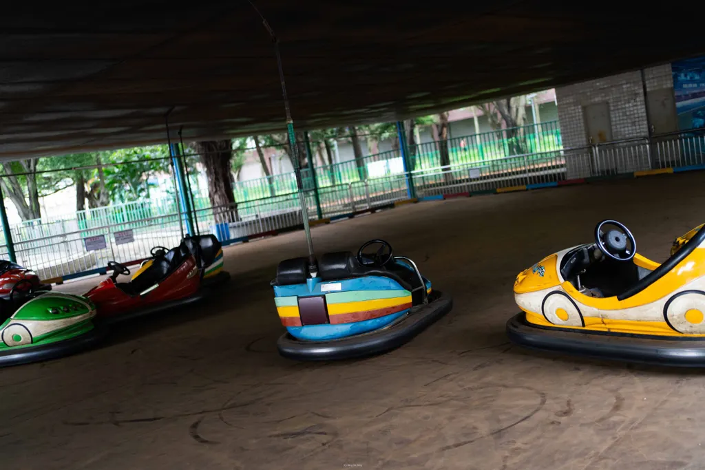 Empty bumper cars sit under a shaded amusement ride structure.