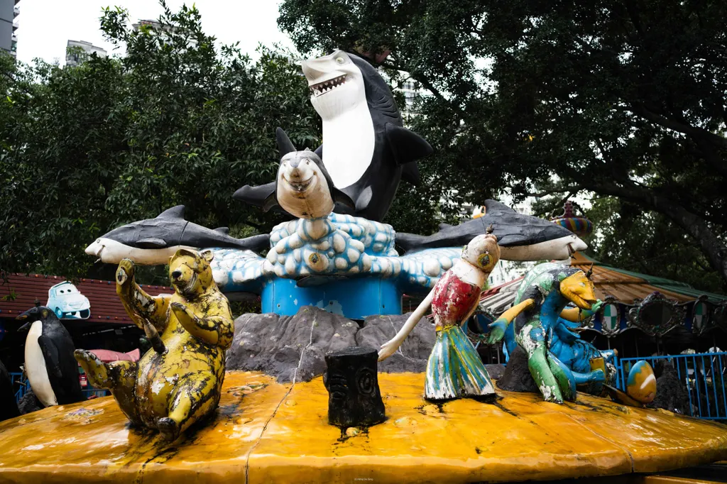 Worn animal figures, including sharks and penguins, stand on an amusement ride platform.